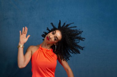 Güzel genç bir kadın saçlarıyla ve kafasıyla hareket ediyor. İzole edilmiş mavi arkaplan.