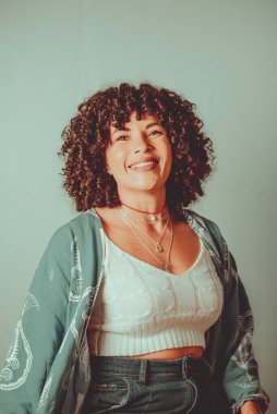 Portrait of cheerful, smiling woman with curly hair. Isolated on light green background.