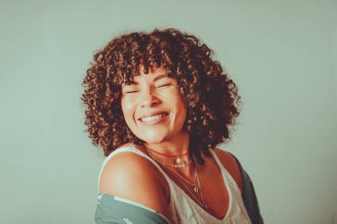 Portrait of cheerful, smiling woman with curly hair. Isolated on light green background.