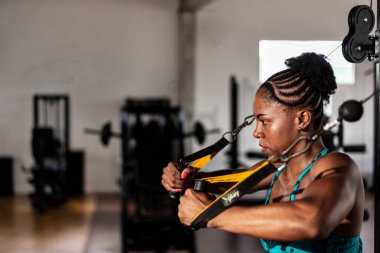 Spor salonundaki makinede kol egzersizi yapan kaslı bir kadın. Kararlılık ve odaklanma.