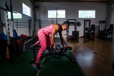 Spor salonunda kol egzersizi yapan kararlı bir kadın. Vücut güçlendirme.