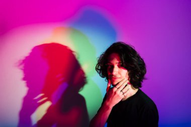 Fotografik arka planda renkli gölgeleri olan genç yakışıklı bir adamın portresi. rgb renkleri