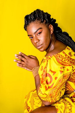 Güzel bir kadının portresi, oturmuş, elleri dua şeklinde. Sarı arkaplanda izole edilmiş.