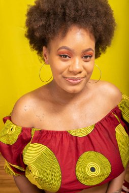 Portrait of beautiful young woman in colorful outfit. Isolated on yellow background.