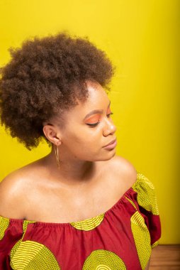 Portrait of beautiful young woman in colorful outfit. Isolated on yellow background.