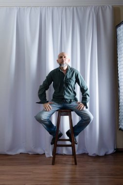 Tahta taburede oturan bir adamın stüdyo portresi. beyaz perde arkaplanı