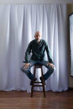 Tahta taburede oturan bir adamın stüdyo portresi. beyaz perde arkaplanı