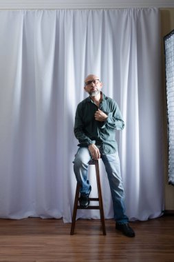 Tahta taburede oturan bir adamın stüdyo portresi. beyaz perde arkaplanı