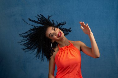 Güzel genç bir kadın saçlarıyla ve kafasıyla hareket ediyor. İzole edilmiş mavi arkaplan.