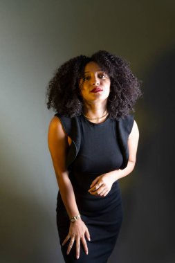 Gri arkaplana karşı duran, kameraya bakan güzel bir genç kadın. Stüdyo resmi