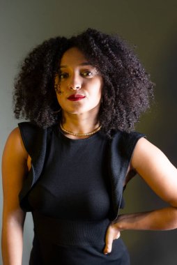 Gri arkaplana karşı duran, kameraya bakan güzel bir genç kadın. Stüdyo resmi