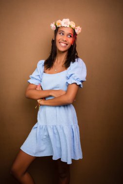 Genç kız, güzel, saç bandı takıyor ve mavi elbise giyiyor. Fotoğraf için poz veriyorum. Kahverengi arkaplanda izole.