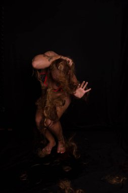 Genç bir adam, aktör, performans gorili şeklinde bikini giyiyor. Tüm vücudu kıllı ve acı dolu. koyu arkaplanda izole.