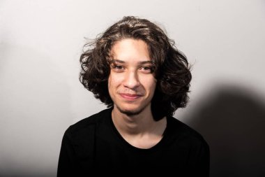 Beyaz arka planda gölgeli uzun saçlı yakışıklı bir adamın portresi..