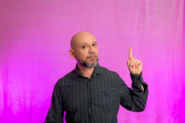 50 yaşında bir adam, komik, parmağını kaldırıyor. Pembe arka planda izole edilmiş.