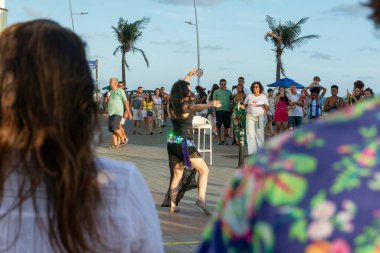 Salvador, Bahia, Brezilya - 22 Ekim 2022: Salvador, Bahia 'daki Farol da Barra' da sokak dansı gösterisini izleyen insanlar.