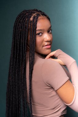 Güzel, mutlu ve kendinden emin saçları örgülü genç bir kadın. Koyu renkli arkaplanda izole edilmiş.