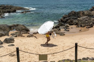 Salvador, Bahia, Brezilya - 14 Ocak 2022: İnsanlar kumsalda şemsiye koyuyorlar. Porto da Barra Plajı, Salvador, Bahia.