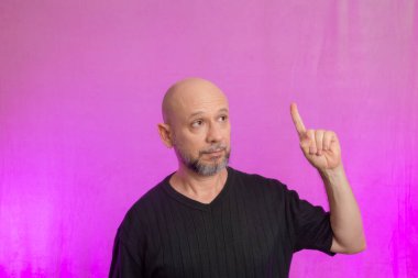 Sakallı ve kel bir adamın portresi. Ellerle tabela yapıyor. Pembe arka planda izole edilmiş.