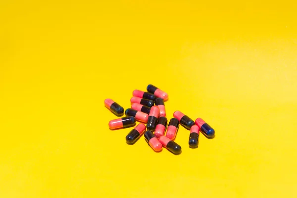 Několik Pilulek Červené Černé Barvy Uspořádaných Žlutém Povrchu Zdravotnické Potřeby — Stock fotografie