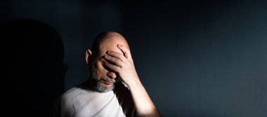 Baş ağrısı ya da migrenden muzdarip üzgün bir adam. Yüzünde acı dolu bir ifade olan stresli bir adam korkunç bir zayıflık ya da depresyon hissediyor. Koyu arkaplanda izole.