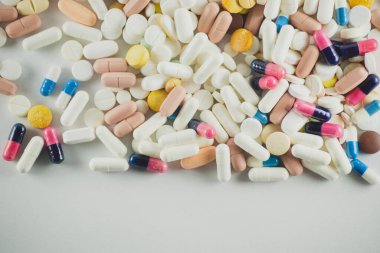 Açık gri bir yüzeye farklı renklerde birkaç hap bırakıldı. Tıbbi malzemeler.