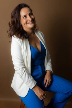 Koçluk yapan kadının portresi, oturmak, kameraya bakmak. Güven, cesaret ve motivasyon kavramı. Kahverengi arkaplanda izole.