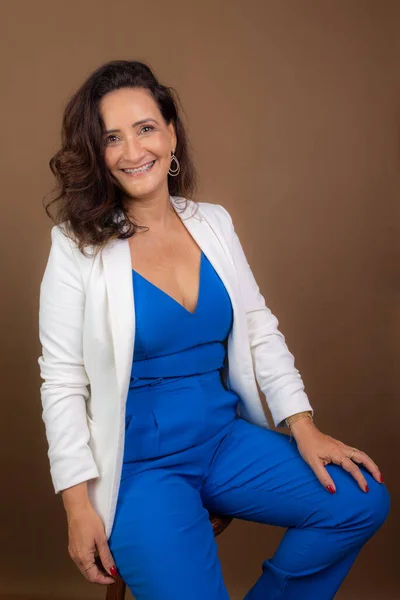 stock image Portrait of coaching woman, sitting, looking at camera. Confidence, encouragement and motivation concept. Isolated on brown background.