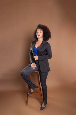 Genç yönetici, zarif ve güzel, tahta bir tabureye yaslanıyor. Başarı konsepti.