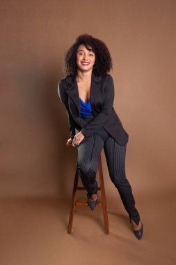 Genç yönetici, zarif ve güzel, tahta bir tabureye yaslanıyor. Başarı konsepti.