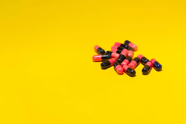 几片红色和黑色的药丸放在一个黄色的表面上 医疗用品 — 图库照片