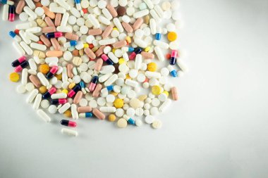 Açık gri bir yüzeye farklı renklerde birkaç hap bırakıldı. Tıbbi malzemeler.