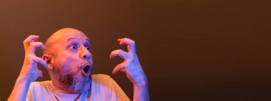 Komik el hareketleri yapan mutlu kel adam. Güç, başarı ve başarı kavramı. Koyu kırmızı arkaplanda izole.