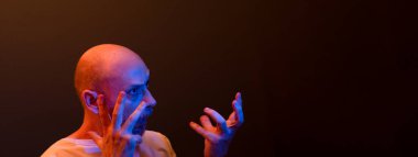 Komik el hareketleri yapan mutlu kel adam. Güç, başarı ve başarı kavramı. Koyu kırmızı arkaplanda izole.