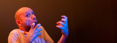 Komik el hareketleri yapan mutlu kel adam. Güç, başarı ve başarı kavramı. Koyu kırmızı arkaplanda izole.