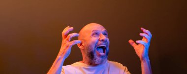 Komik el hareketleri yapan mutlu kel adam. Güç, başarı ve başarı kavramı. Koyu kırmızı arkaplanda izole.