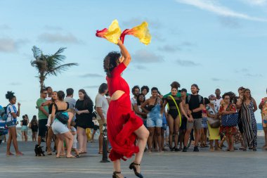 Salvador, Bahia, Brezilya - 22 Ekim 2022: Salvador, Bahia 'daki Farol da Barra' da bir sokak sanatçısının dans gösterisi sırasında insanlar görülüyor.