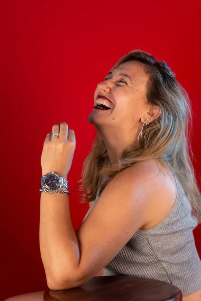 Uśmiechnięta Piękna Kobieta Siedząca Szarej Bluzce Izolacja Czerwonym Tle — Zdjęcie stockowe