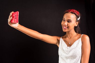 Ergen, gülümseyen, cep telefonuyla selfie çeken. Siyah arkaplanda izole.