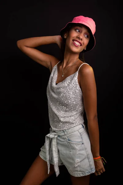 スタジオで写真のポーズをとっている美しい10代の女の子 ピンクの帽子をかぶって 黒の背景に隔離された — ストック写真