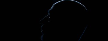 Kafası arka planda olan bir adamın silueti. Stüdyo portresi. Koyu arkaplanda izole.