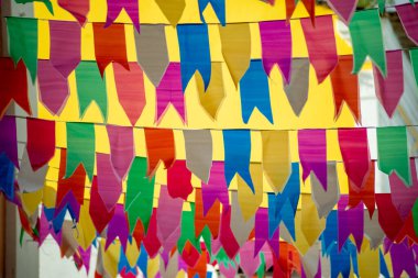 İpe asılı farklı renkte bayraklar. Sao Joao 'nun dekorasyonu. Haziran kutlaması. Sarı duvara yaslan.