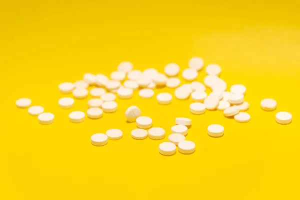 Několik Bílých Pilulek Umístěných Žlutém Povrchu Zdravotnické Potřeby — Stock fotografie