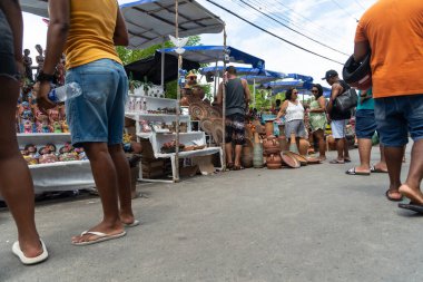 Nazare das Farinhas, Bahia, Brezilya - 08 Nisan 2023: İnsanlar Nazare das Farinhas, Bahia sokaklarındaki Caxixis fuarı sırasında seramiklerden yapılan resimlere bakarken görülüyor.