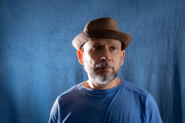 Fotoğraf için poz veren sakallı bir adamın portresi. Mavi arkaplanda izole.