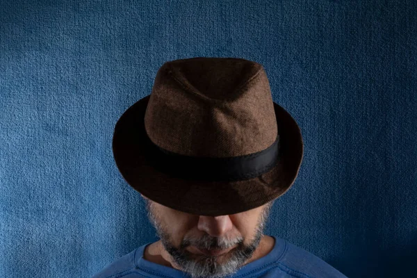頭を下げ ジェスチャーで帽子をかぶっている男のスタジオの肖像画 青い背景に隔離された — ストック写真