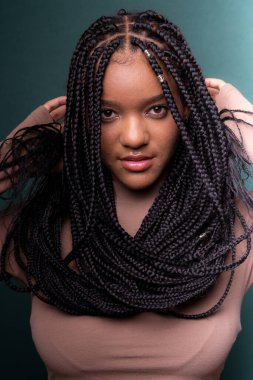 Güzel, mutlu ve kendinden emin saçları örgülü genç bir kadın. Koyu renkli arkaplanda izole edilmiş.