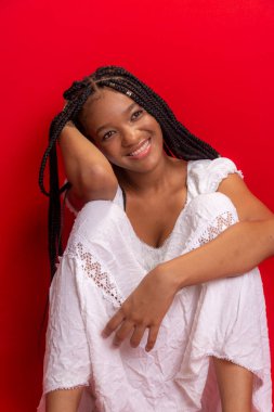 Güzel siyah kadın kameraya gülümsüyor. Kırmızı arkaplanda izole