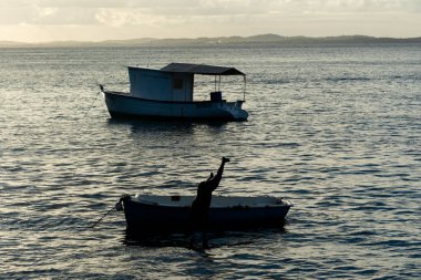 Salvador, Bahia, Brezilya - 14 Ocak 2022: Salvador, Bahia 'daki Modern Sanatlar Müzesi' nin sahilinde eğlenen küçük bir teknedeki insanların silueti.