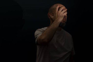 Baş ağrısı ya da migrenden muzdarip üzgün bir adam. Yüzünde acı dolu bir ifade olan stresli bir adam korkunç bir zayıflık ya da depresyon hissediyor. Koyu arkaplanda izole.